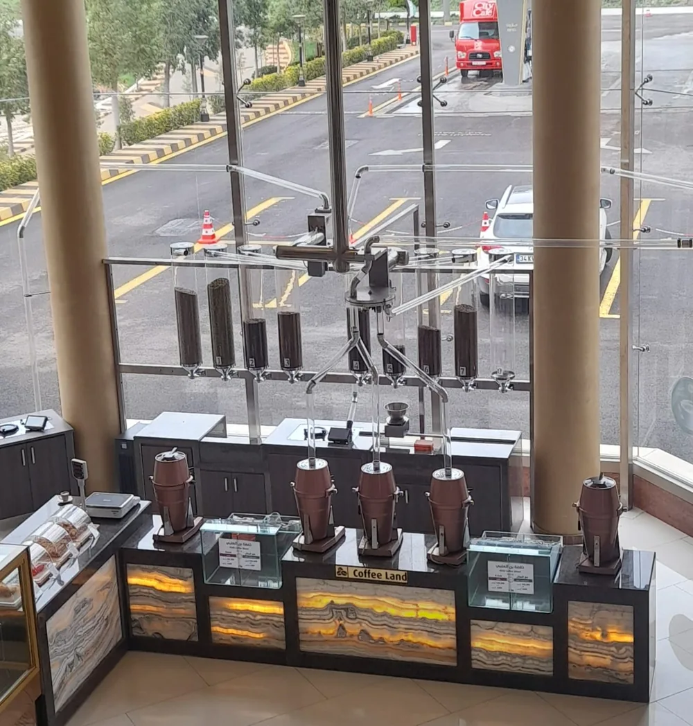 Overhead pneumatic tubes carrying coffee beans from numbered hoppers to counter grinders